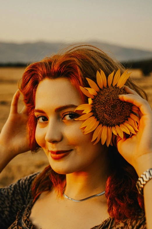 a pretty young lady holding a large sunflower