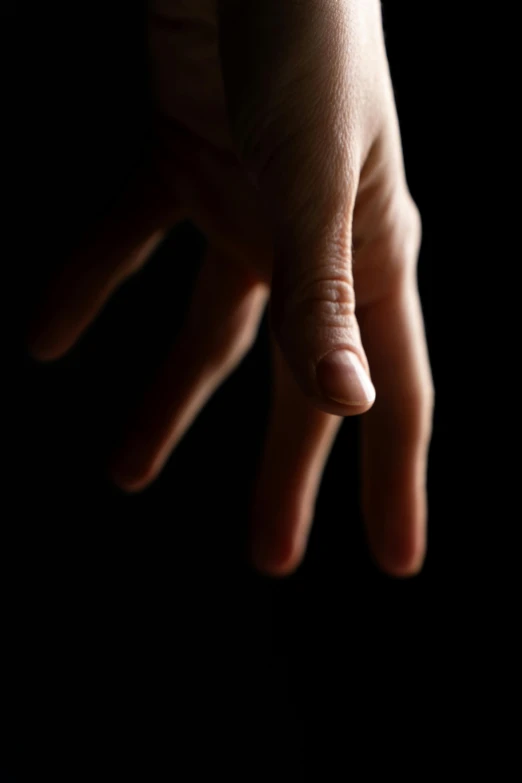 a person's hand that is reaching up to touch a white object