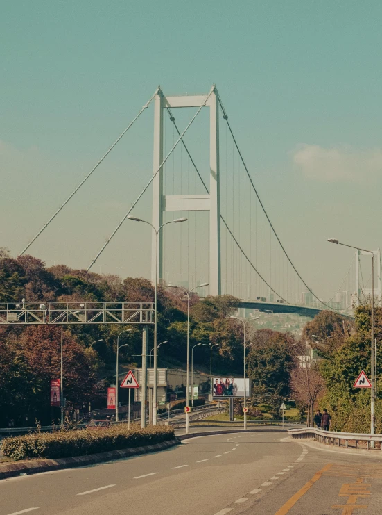 the street near the bridge is empty and people are standing on it