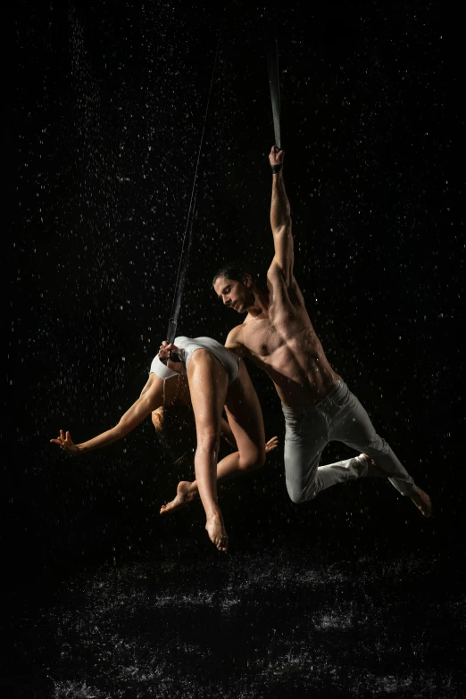 two male dancers on the ground in the rain