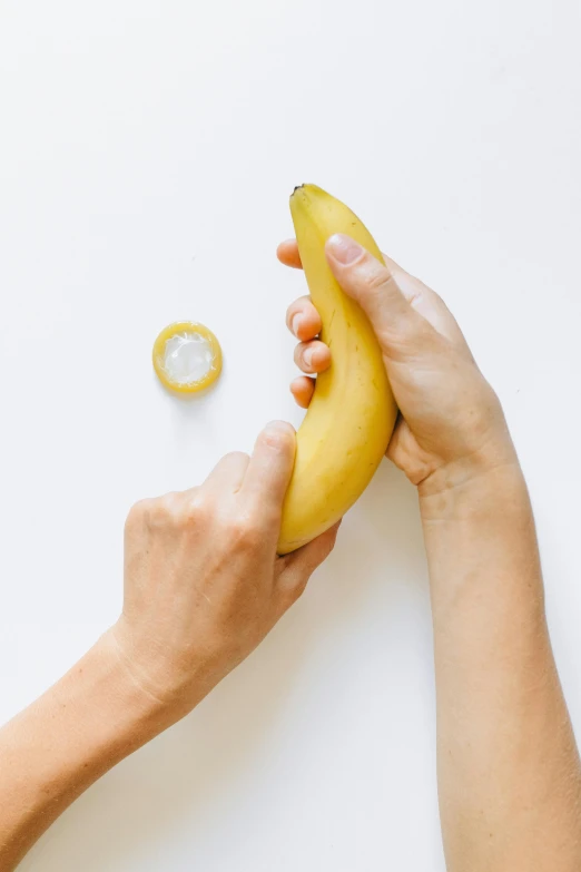 a person holding a banana and a yellow piece of fruit