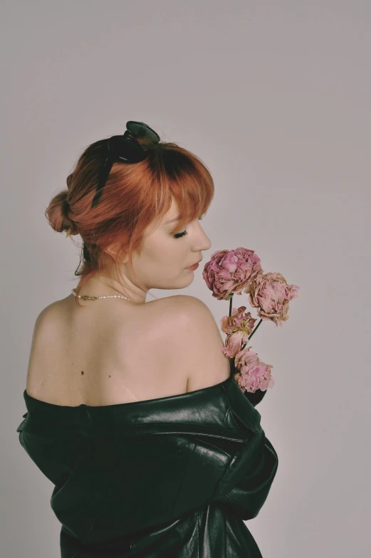 a woman in a black dress holding pink flowers