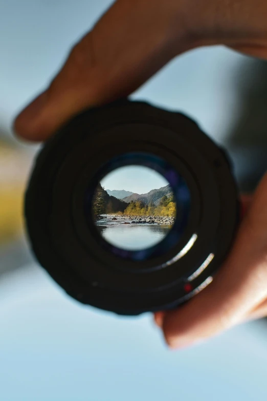 a camera lens being reflected in the middle of its hand