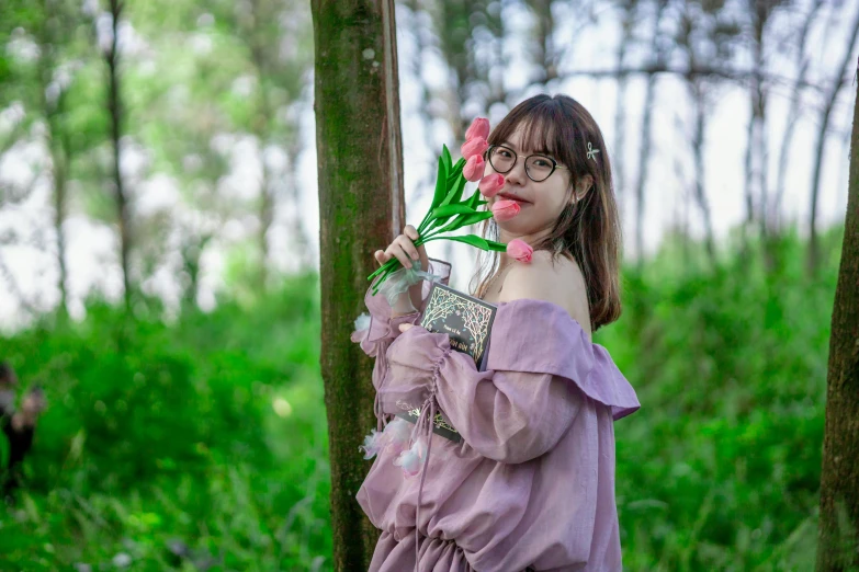 a girl in a purple outfit stands next to a bunch of trees with pink flowers