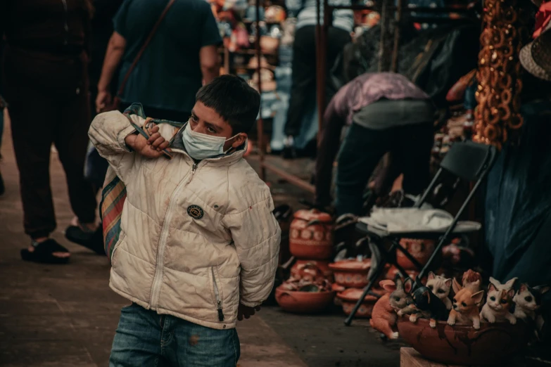 a boy wearing a face mask in front of a market