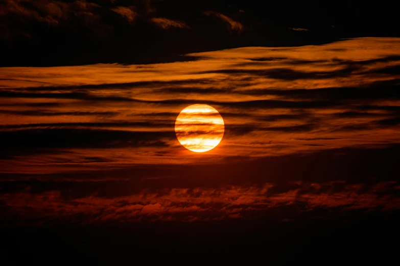 the sun is seen behind clouds and at night