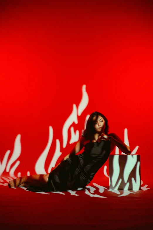 a woman in a black dress and flame designs on red wall