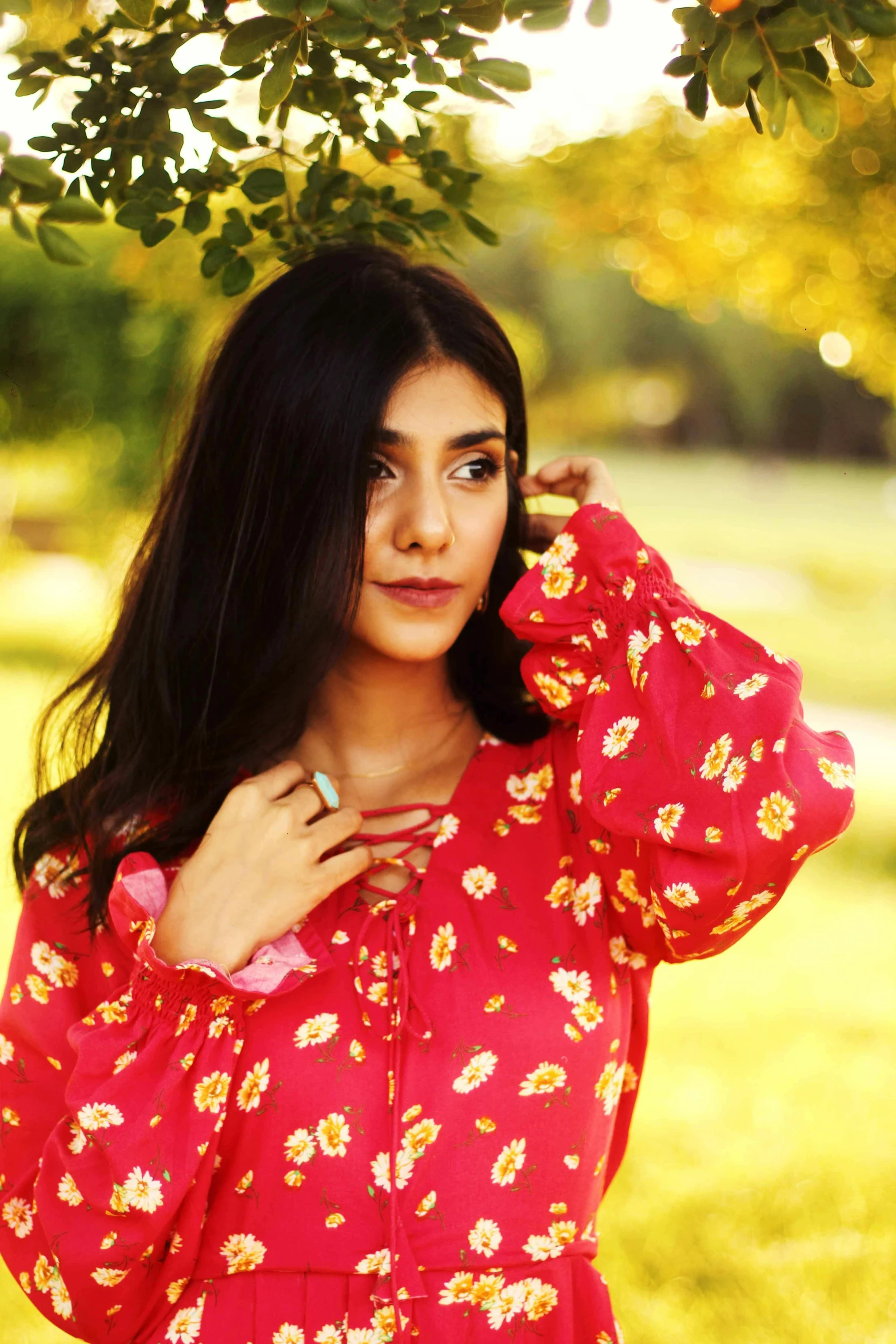 a woman in a red dress stands under a tree