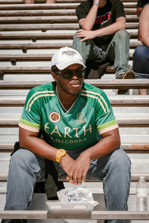 a man wearing a hat while sitting on some bleachers