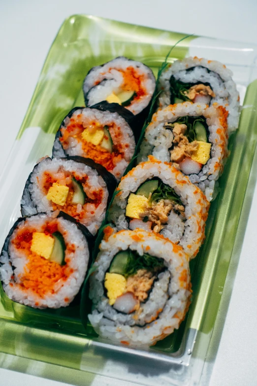 sushi arranged in square plastic tray on white table