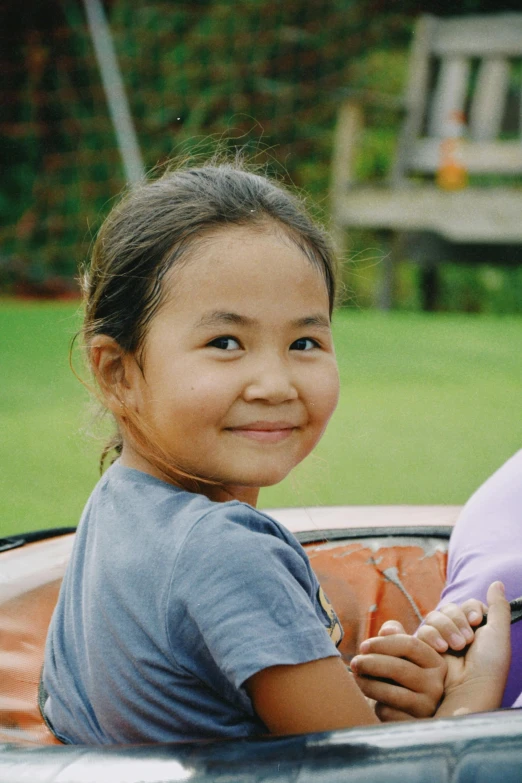 a little girl smiles while sitting in the back of a car