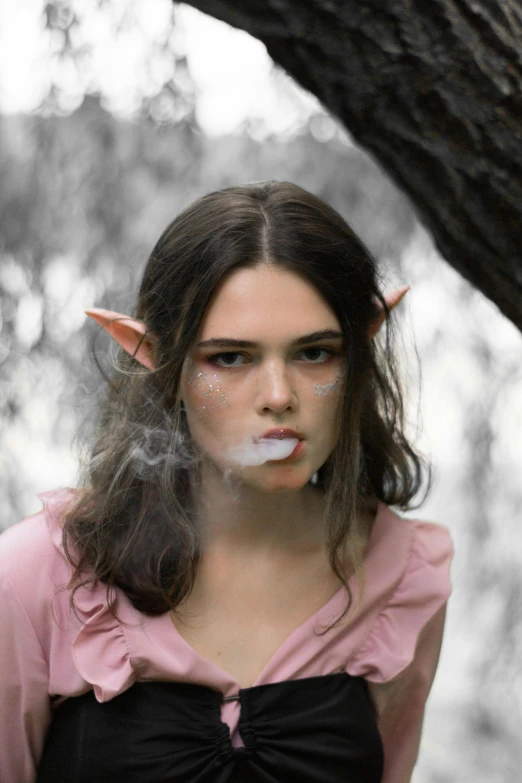 woman with cigarette in hand wearing a pink shirt and black and white outfit