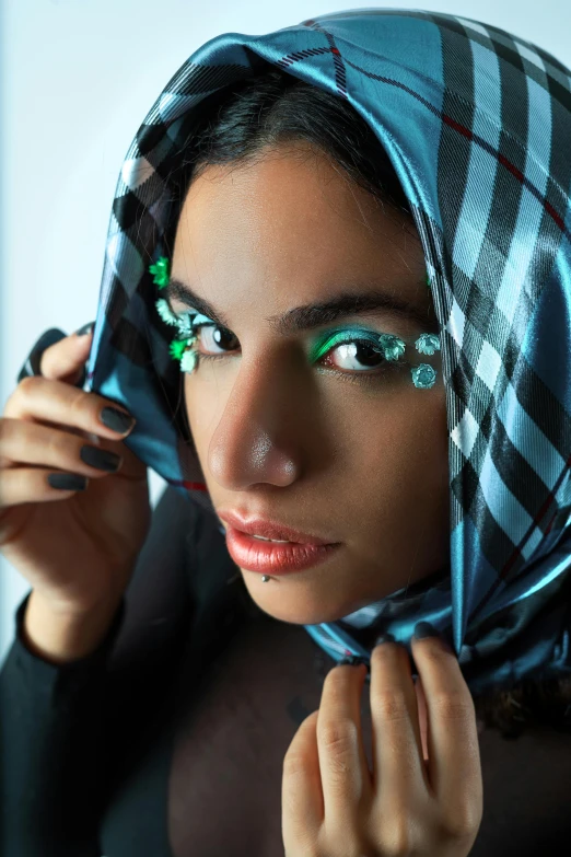 a beautiful young woman wearing a blue bandanna and green eye shadow