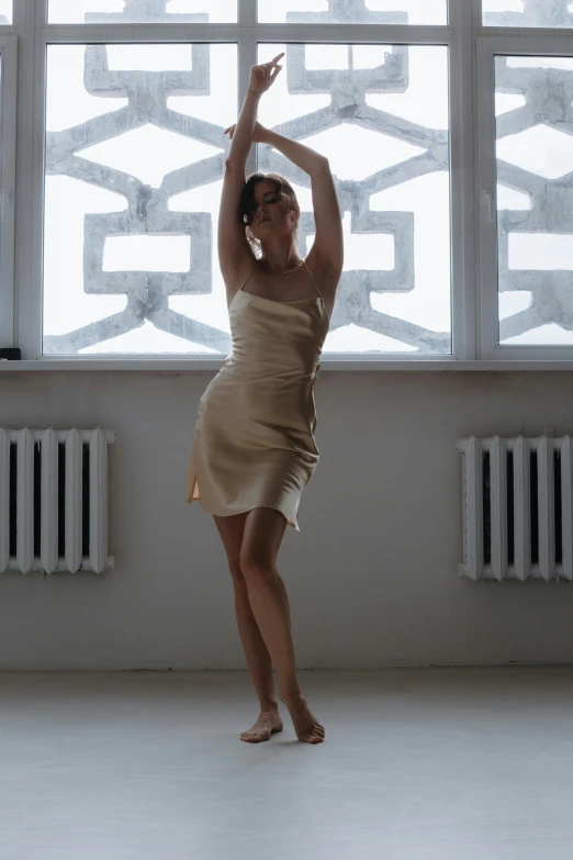 a woman dressed in beige is standing in the middle of a dance