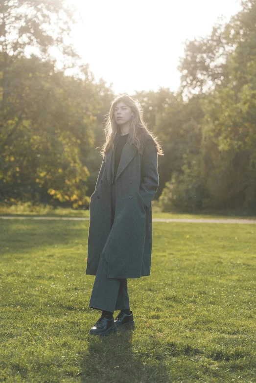 a young woman standing in a grassy field on a sunny day