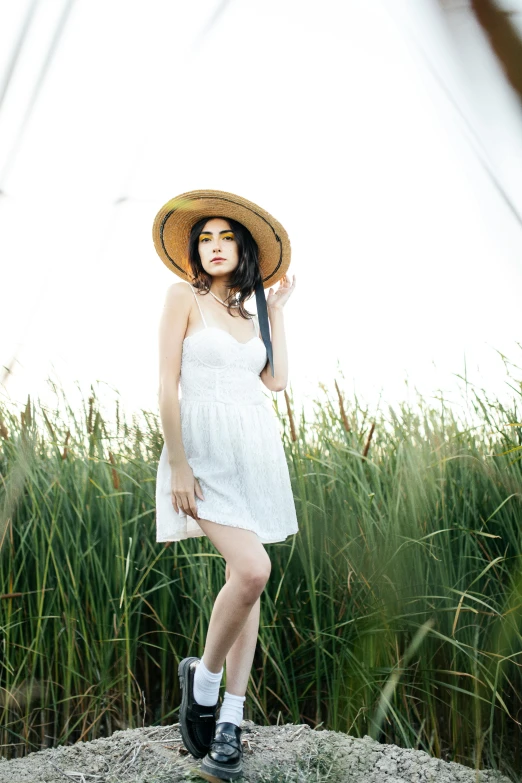 an asian woman is posing in a white dress and hat