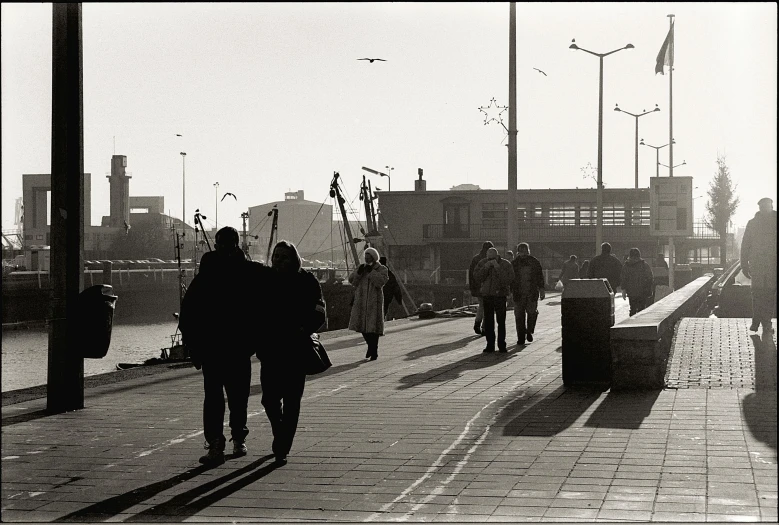 people walking on the sidewalk next to the water