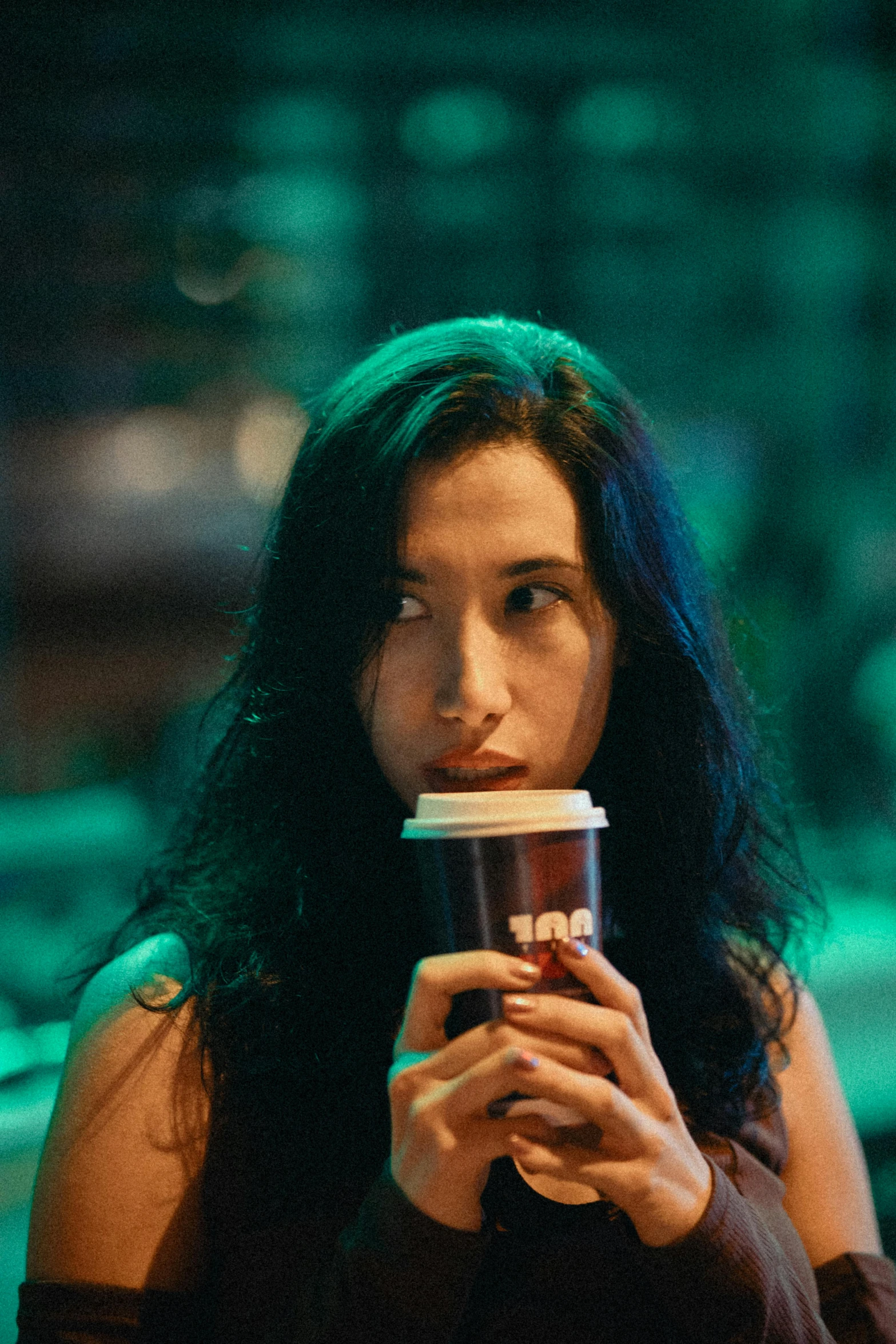 a woman drinking out of a cup in her hand