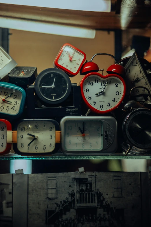 multiple antique clock sitting on display next to a wooden shelf