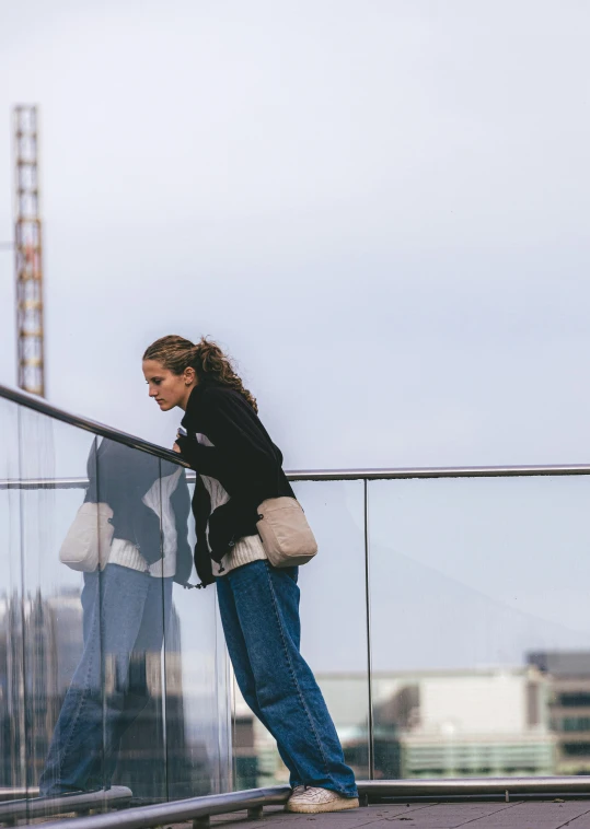 a girl looks at her phone on a glass fence