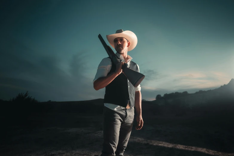 the man is holding up his rifle as he stands in the field