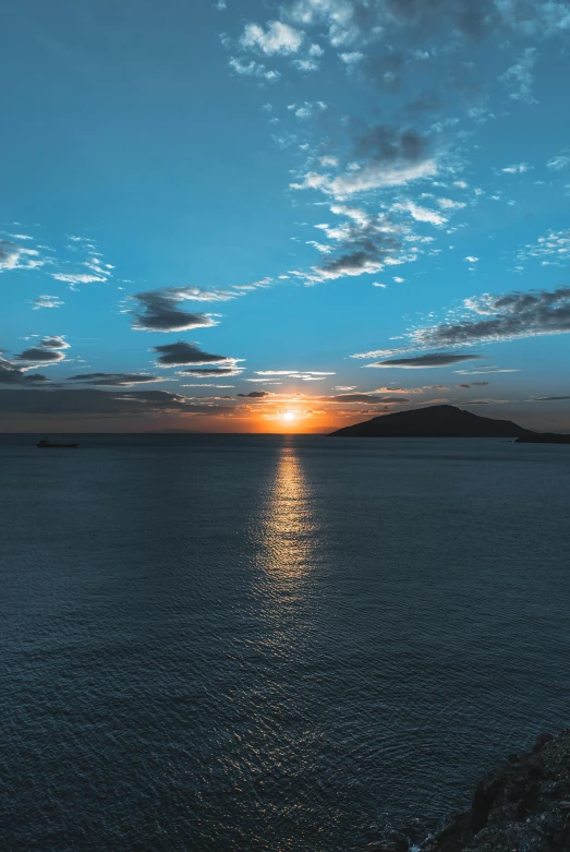 a small boat sailing on top of the ocean under a sunset