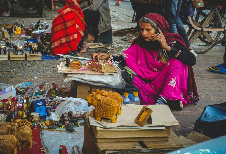 a lady is on her cell phone next to several crates, boxes and food