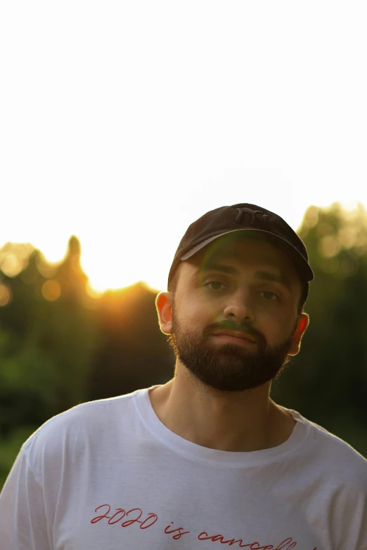 a bearded man with a baseball cap is staring off in the distance