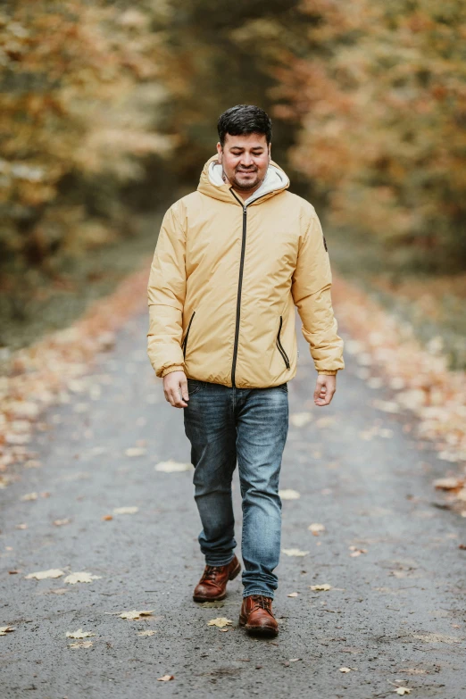 man walking down a leaf covered road during fall