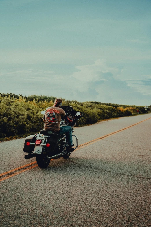 man riding motorcycle down road in the middle of green grass