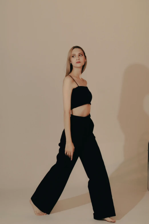 woman in wide legged black pants and crop top poses