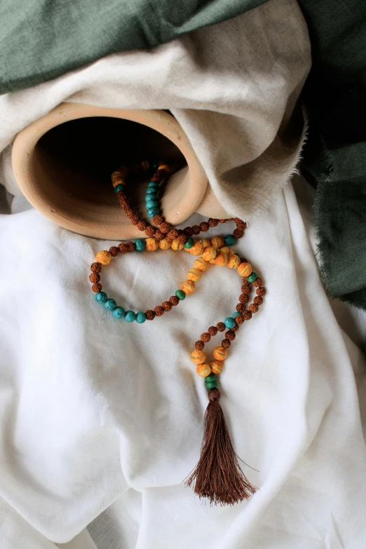 an unshaven necklace with tassels and beads on top of a blanket