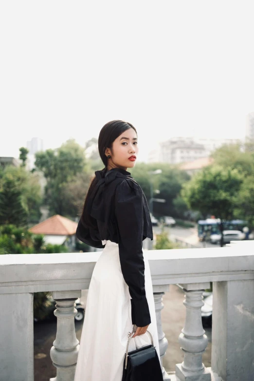 a woman wearing a black and white top holds a handbag