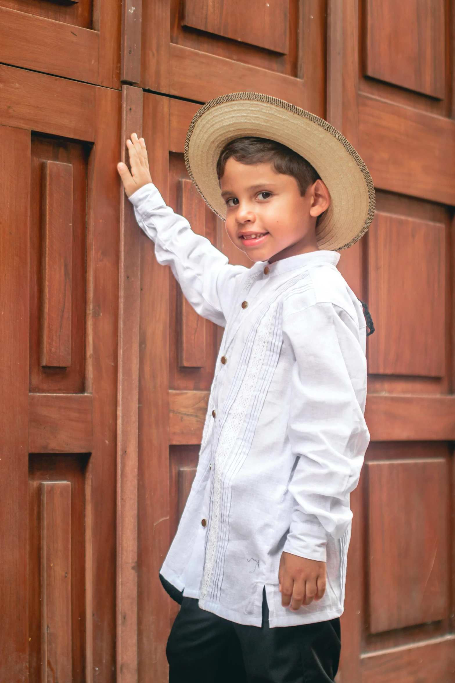 a small boy is holding onto the back of a wooden door