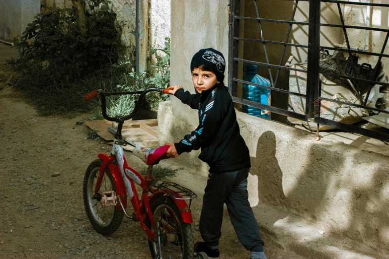 young child riding a bicycle in front of a cage