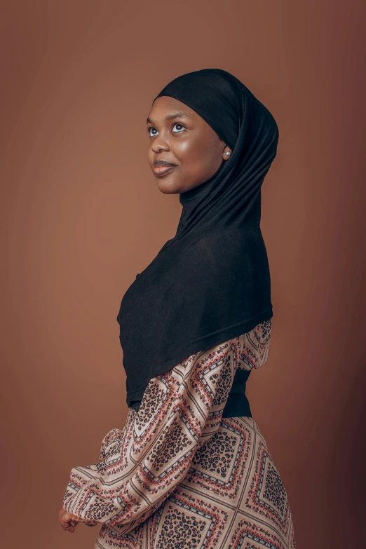 an older woman is standing in front of a brown wall