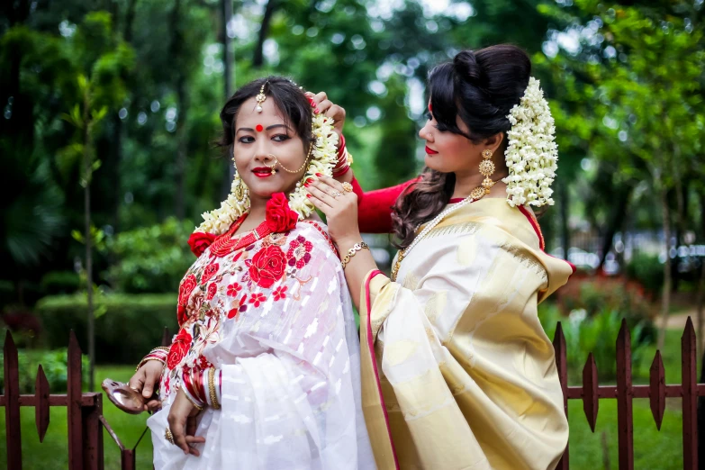 two women pose for a po in traditional wedding dress