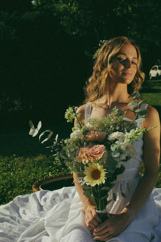 a beautiful woman wearing a wedding dress is sitting down holding a bouquet