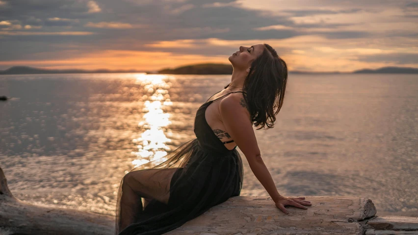 a woman sitting on a log near the ocean