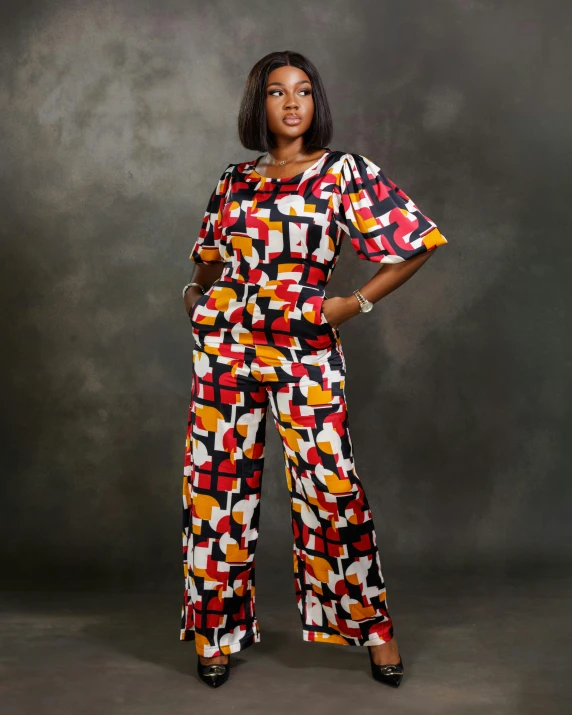 a woman wearing multicolored clothing standing in front of a black wall