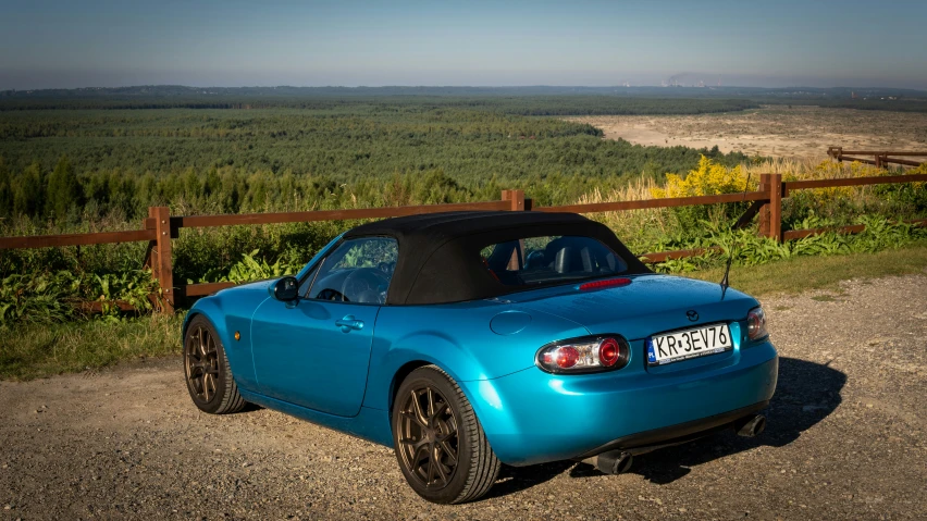 a sports car is parked near a road and some woods