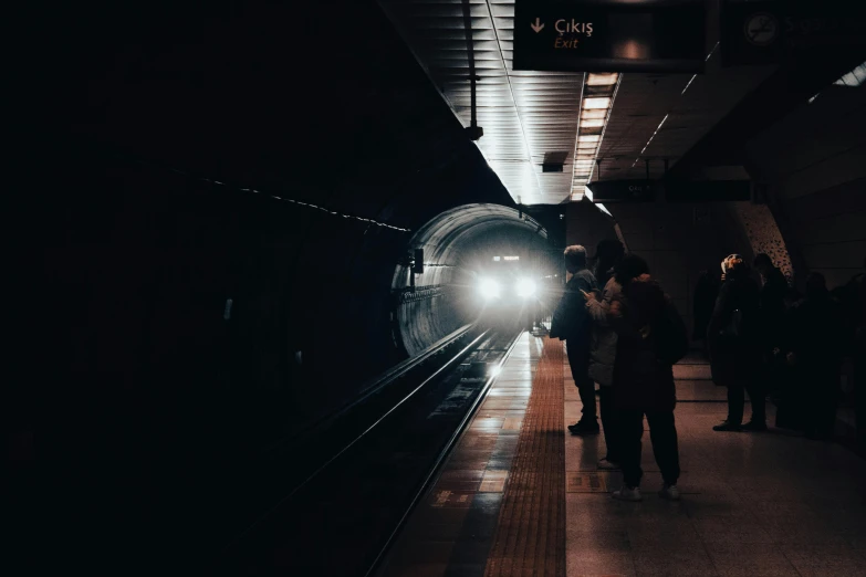 a group of people standing in a train station near a tunnel