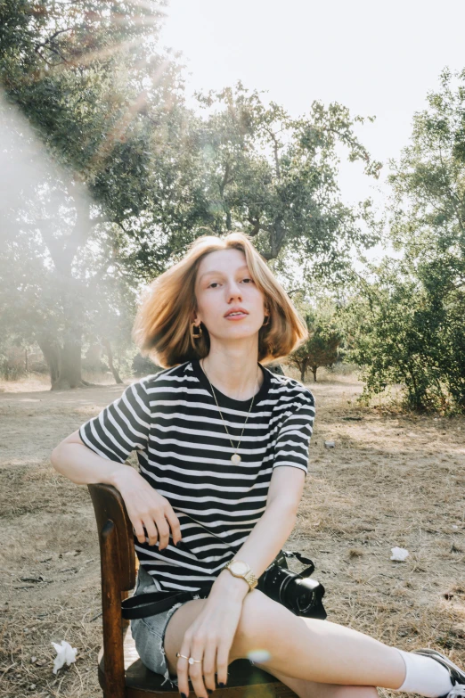 a young woman sitting on a bench in a wooded area