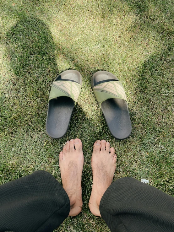 a person in flip flops standing on green grass