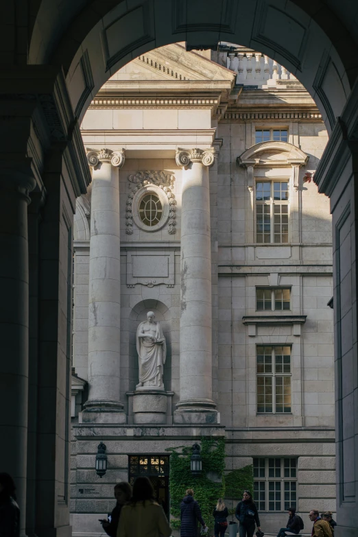 people walking by an old building with columns