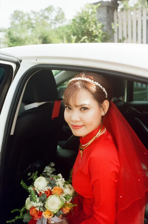 a woman in a red gown sitting in the back of a car