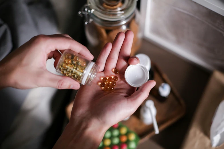 a person holds a glass jar with several different pill bottles in it