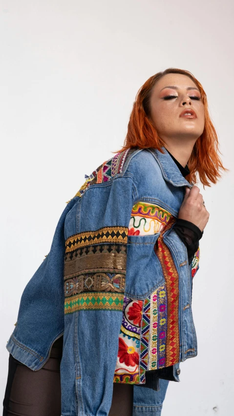 a girl in a denim jacket with an artistically designed jacket over her shoulders