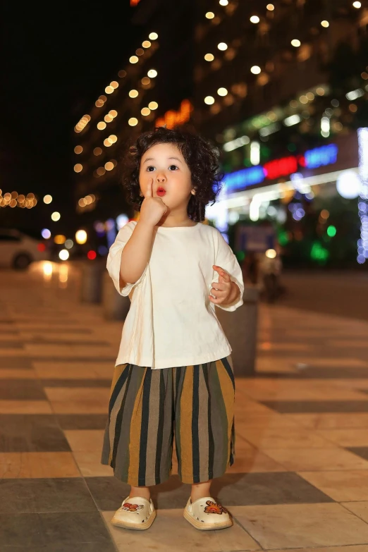 the little girl is holding her hand up to her mouth