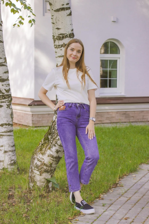 a girl standing by the side of the road in purple pants